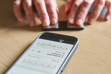 Close up of woman using wireless monitor and app on phone to check heart rate