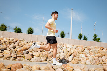 Running enthusiast exercises along a stony path under a clear blue sky