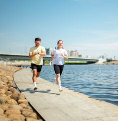 Sunny day joggers enjoying a lively run along a serene riverside pathway
