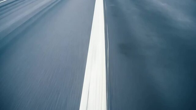 Fast motion camera moves rapidly along highway showing white dashed road markings and lane dividers creating dynamic speed blur effect with asphalt pavement rushing past