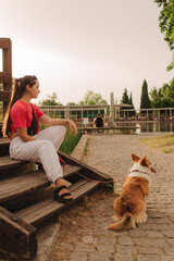 Close-up of a woman with Welsh Corgi in a park on a hot sunny day. Concept of pet care and...