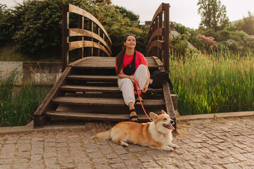 Close-up of a woman with Welsh Corgi in a park on a hot sunny day. Concept of pet care and...
