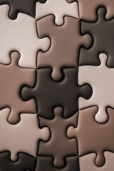 Puzzle pieces background with various shades of brown, close-up view. Textured jigsaw puzzle