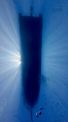 Bottom view of a boat silhouette on the water surface. Motorboat on the sea surface. Silhouette of a boat on the ocean surface against the sun.