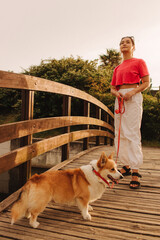 Close-up of a woman with Welsh Corgi in a park on a hot sunny day. Concept of pet care and...