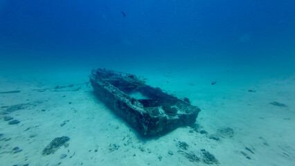 A sunken boat on the seabed. A small boat on the sandy ocean floor underwater. A sunken boat...