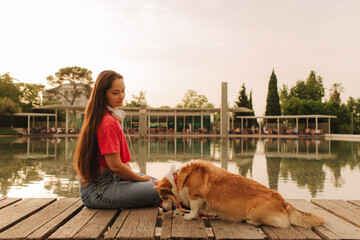 Close-up of a woman with Welsh Corgi in a park on a hot sunny day. The dog looks tired from the...