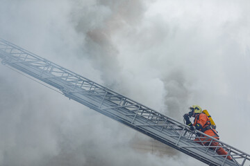 Firefighter Climbing Ladder Through Thick Smoke During Emergency Rescue Operation at Burning...