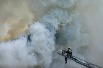 Firefighter Battling Smoke and Flames on Ladder During Emergency Rescue Operation