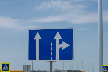 Road sign displays directions for vehicles traveling straight or turning right at a busy urban...