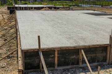 New concrete stretches across the site, framed by wood, showing progress in the building process...