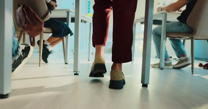 Legs, person and teacher walking in classroom to monitor students, exam supervision and protocol. Feet, lecturer and invigilation of assessment, prevent cheating and maintain order of time management