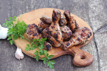 Grilled chicken legs on cutting board. Wooden rustic background.