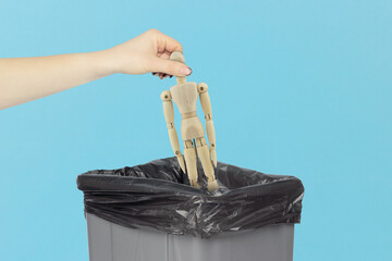 Throw wooden man, in the trash, outstretched hand with wooden mannequin in front of trash can