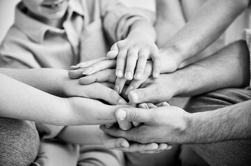 Close-up of several hands placed on top of one another in stack. Big family putting stacked hands...