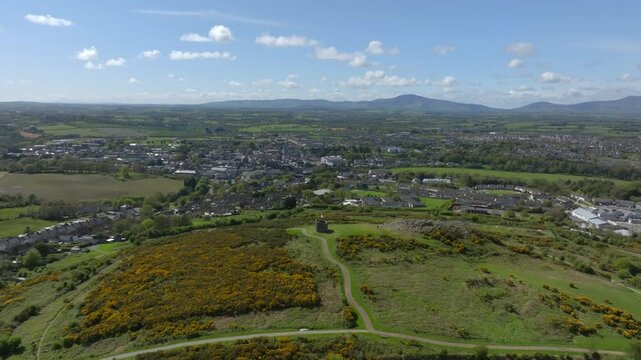 Vinegar Hill, Enniscorthy, County Wexford, Ireland, April 2025. Drone establishing panoramic overview of stone tower monument with buildings in backdrop, descends to elevate and highlight tower.