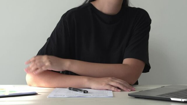 Young asian business woman is suffering pain on wrist, finger and arm, arthritis inflammation while working. Woman is massaging herself and doing exercise with her hands to relax and to relieve pain.