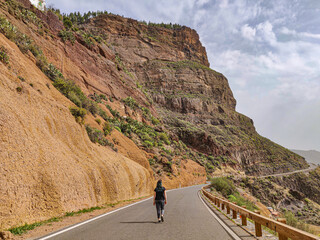 Scenic view of a woman walking along a picturesque winding road near Tejeda. Gran Canaria, Canary...