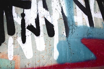Urban graffiti on a concrete wall featuring bold black, white strokes. 90s, Y2K aesthetic, spray paint texture, vibrant colors. Street art, murals, creative city visuals, modern 90s, Y2K design.