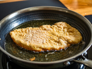 Frying crispy breaded chicken cutlets in frying pan, close-up