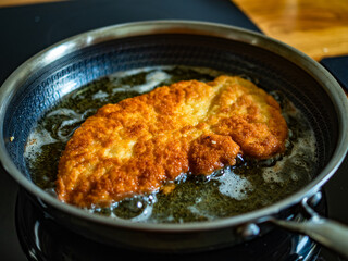 Frying crispy breaded chicken cutlets in frying pan, close-up
