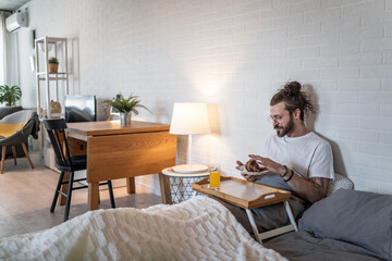 Freelancer enjoying breakfast in bed while working from home