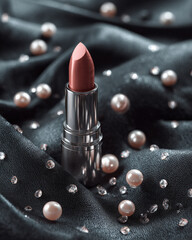 Luxurious lipstick placed elegantly on dark fabric, surrounded by shimmering pearls and sparkling diamonds, creating glamorous and sophisticated atmosphere