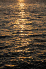 Golden rippled water surface at sunset, abstract and serene