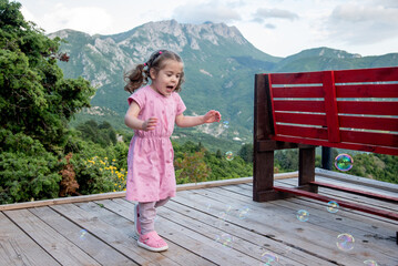 Cute funny little girl toddler child blowing soap bubbles in park summer outside
