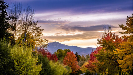 Obraz premium Vibrant autumn trees frame a majestic mountain under a colorful twilight sky