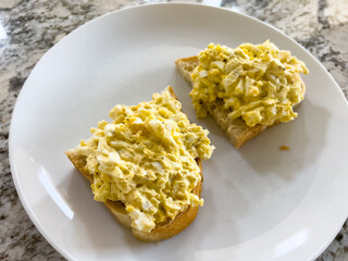 Open-faced egg salad sandwich on white plate