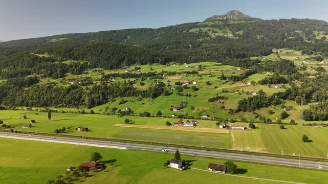 Scenic Aerial View of Swiss Train Passing Through Alpine Valley with Green Fields and Mountains Near Flums, Berschis and Walenstadt, Switzerland &ndash; Drone Footage