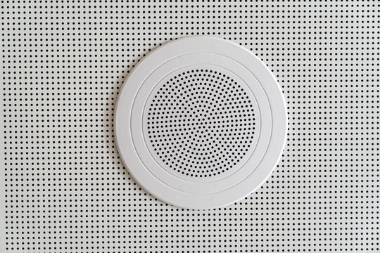 Close up view of a speaker on a white background, on a wall or ceiling.