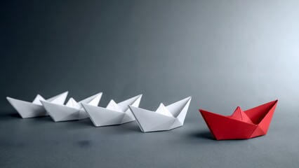 A conceptual representation of leadership, strategy, and vision featuring a red paper boat leading a group of white paper boats on a gray background emphasizing difference and guidance.
