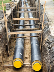 Underground installation of preinsulated district heating pipes in urban environment. Ideal for: energy infrastructure, sustainable heating systems, and civil engineering documentation.