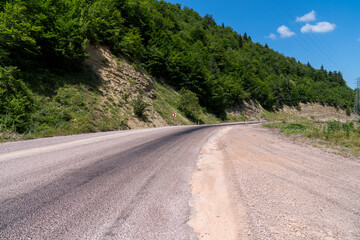 Winding road in the countryside in the mountains with blue sky and clouds.