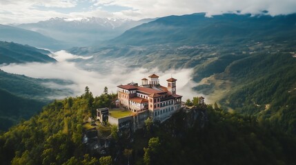 Fototapeta premium Aerial view of a majestic monastery perched atop a rocky cliff surrounded by misty mountains.