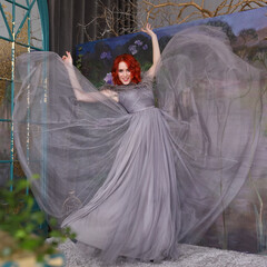 Beautiful girl with red hair in a long gray dress
