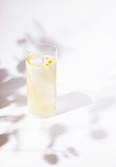 A sleek and modern cocktail served in a tall, clear glass with a single large ice shard and...