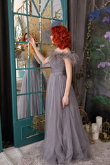 Beautiful girl with red hair in a long gray dress