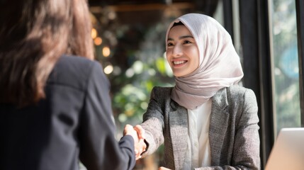 Two businesswomen shaking hands in a cafe