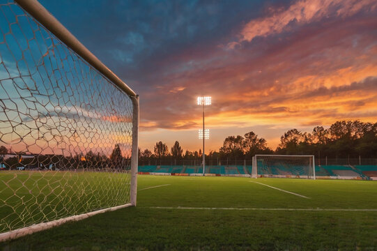 Soccer field goal net stadium lights sunset sky football