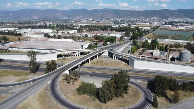 Aerial view of highway overpassing and road loops at Ciudad Guzman with hills in the background