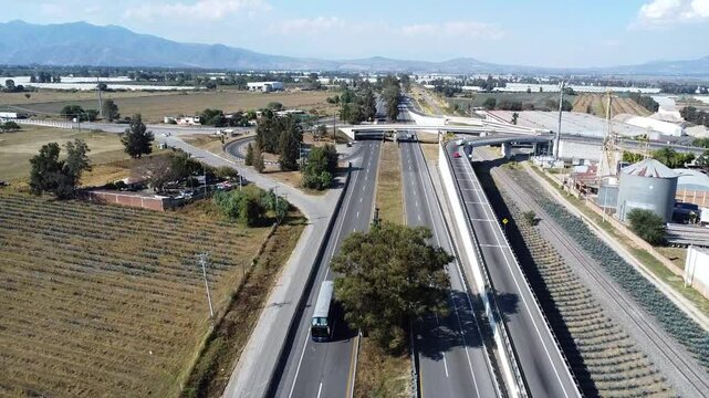 Carriageway flanked by farmland and overpasses near Ciudad Guzman with clear skies and distant hills