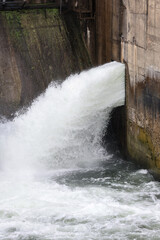 Overflow gate opened on a big concrete dam. Large volume of water flowing at high pressure.