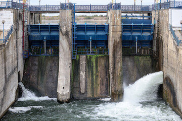 Overflow gate opened on a big concrete dam. Large volume of water flowing at high pressure.