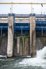 Overflow gate opened on a big concrete dam. Large volume of water flowing at high pressure.