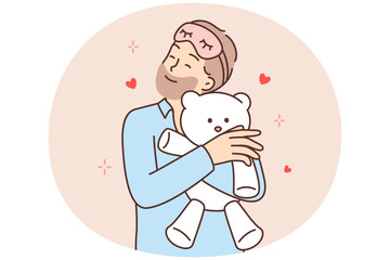Funny bearded man hugging teddy bear before going to bed feeling attached to gift toy
