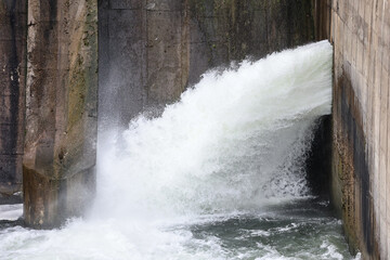 Overflow gate opened on a big concrete dam. Large volume of water flowing at high pressure.