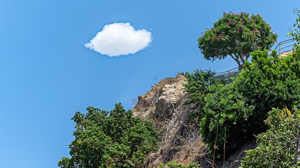 Obraz premium Scenic landscape featuring lush vegetation and a fluffy cloud under a clear blue sky